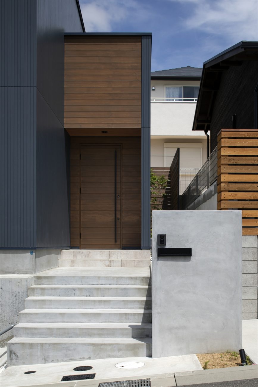 コンクリートの階段を上がった先にある木製の扉の玄関・デザイン住宅 注文住宅・デザイン住宅建築実例_『CASE629 Con』_外観