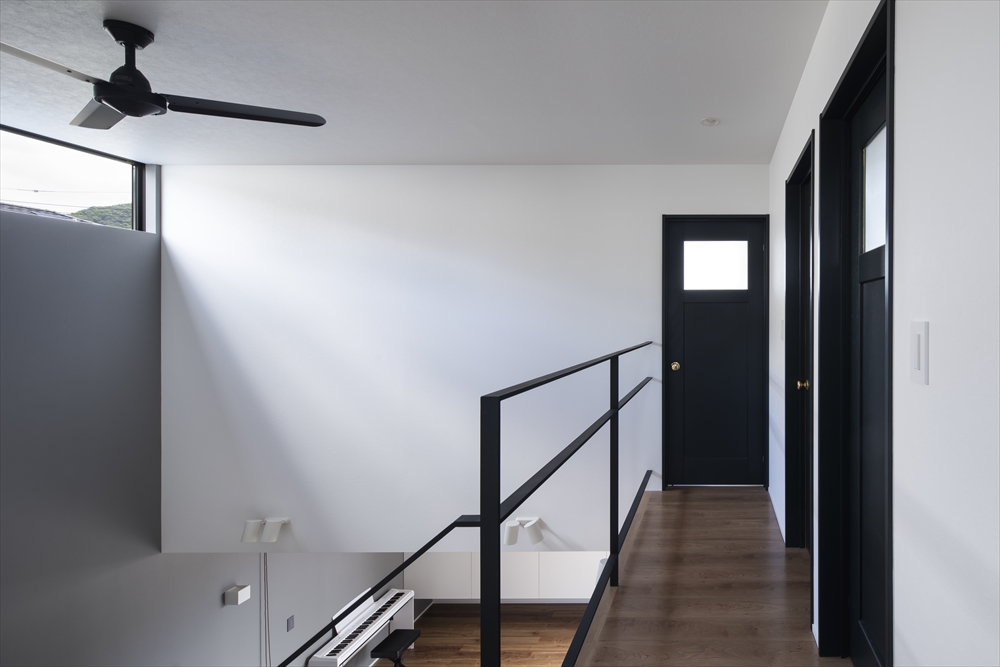 窓付きの黒い扉が付いた部屋がある吹き抜けに面した廊下・デザイン住宅 注文住宅・デザイン住宅建築実例_『CASE629 Con』_廊下