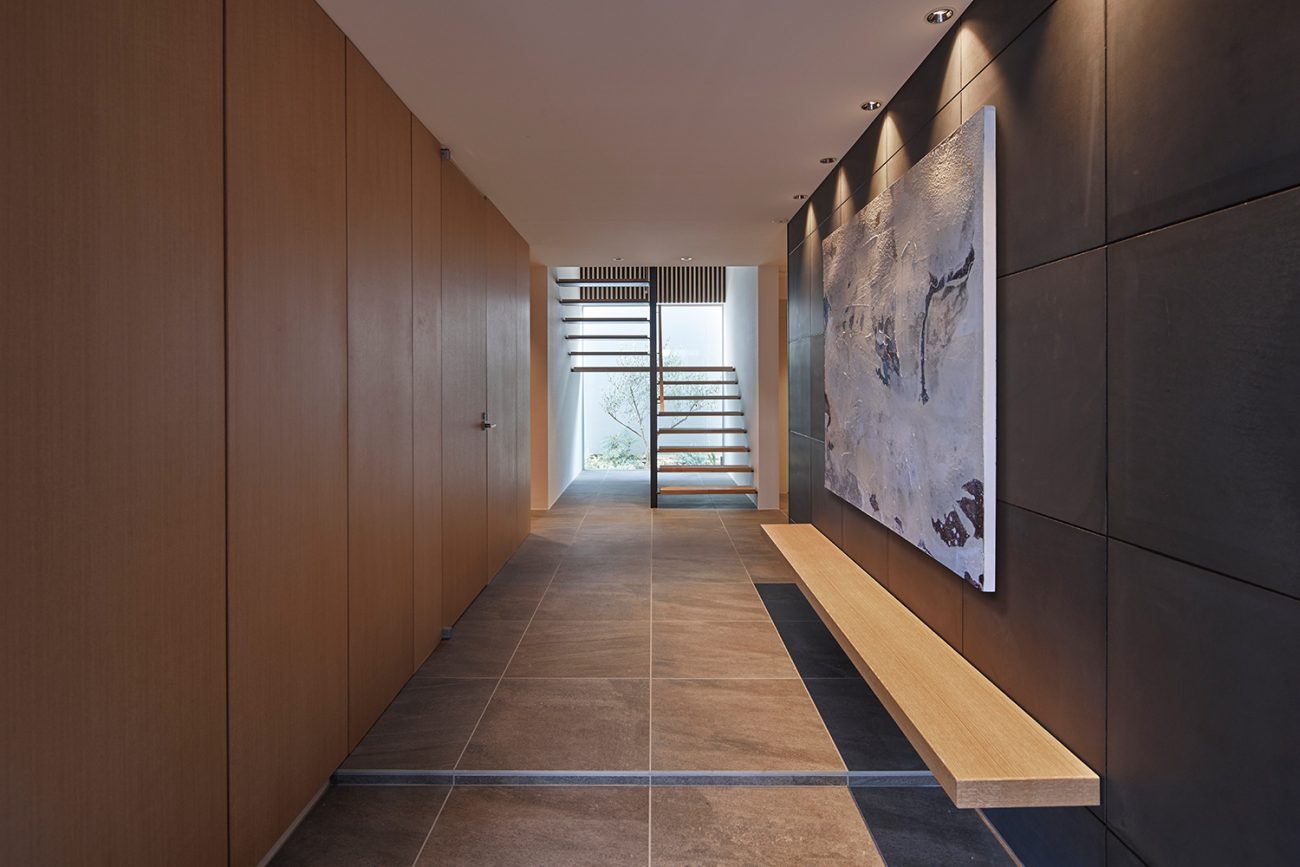 壁に木製のベンチが取り付けられた正面に窓とスケルトン階段がある玄関・デザイン住宅 注文住宅・デザイン住宅建築実例_『CASE632 H邸（社長の邸宅）』_玄関