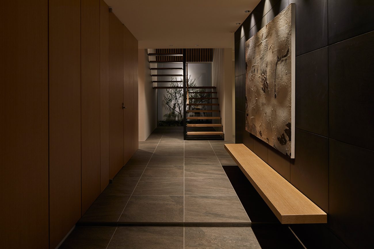 壁付けのベンチがあり、正面には照明に照らされた植栽が見える玄関・デザイン住宅 注文住宅・デザイン住宅建築実例_『CASE632 H邸（社長の邸宅）』_玄関