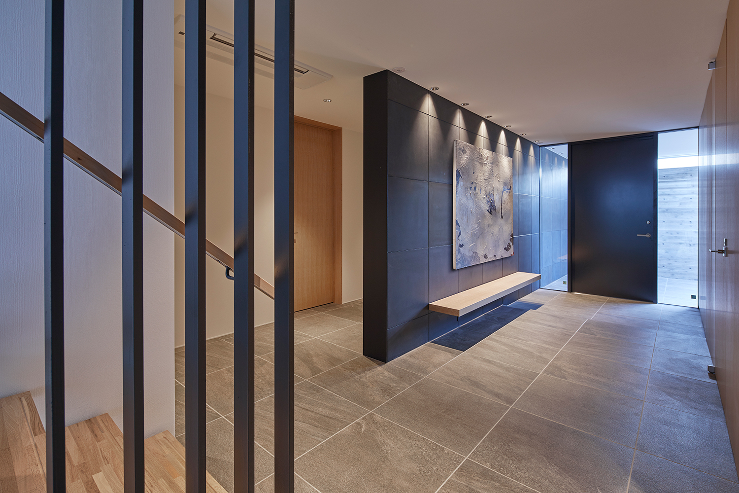 グレーのタイル床で、木製のベンチが取り付けられた黒い壁がある玄関・デザイン住宅 注文住宅・デザイン住宅建築実例_『CASE632 H邸（社長の邸宅）』_玄関