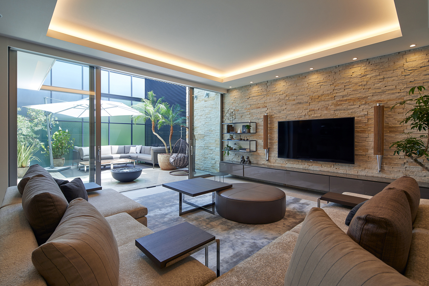 テレビがついている壁が石のアクセントウォールになっているLDK・デザイン住宅 注文住宅・デザイン住宅建築実例_『CASE678 K邸（社長の邸宅）』_LDK