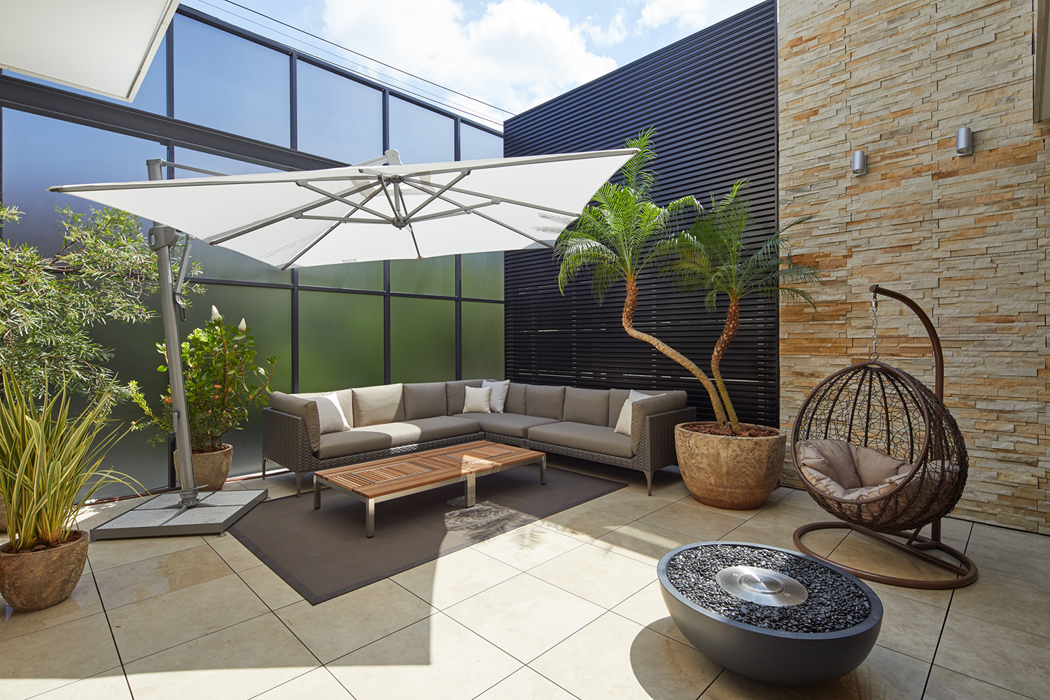 パラソルのついたL字ソファーやハンモックチェアが置かれたバルコニー・デザイン住宅 注文住宅・デザイン住宅建築実例_『CASE678 K邸（社長の邸宅）』_テラス・バルコニー