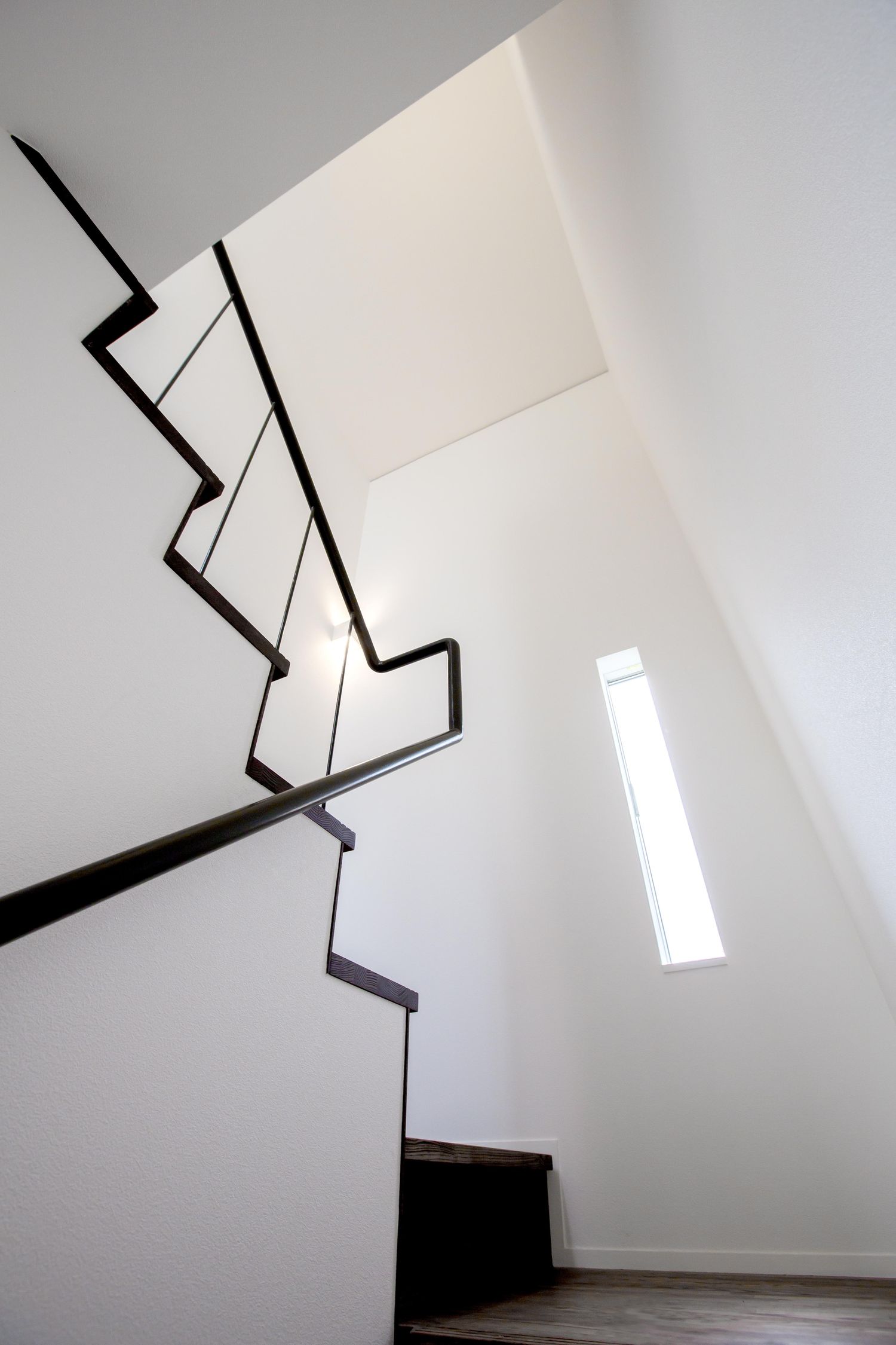 黒くて細い手すりが取り付けられた白い箱型階段・デザイン住宅