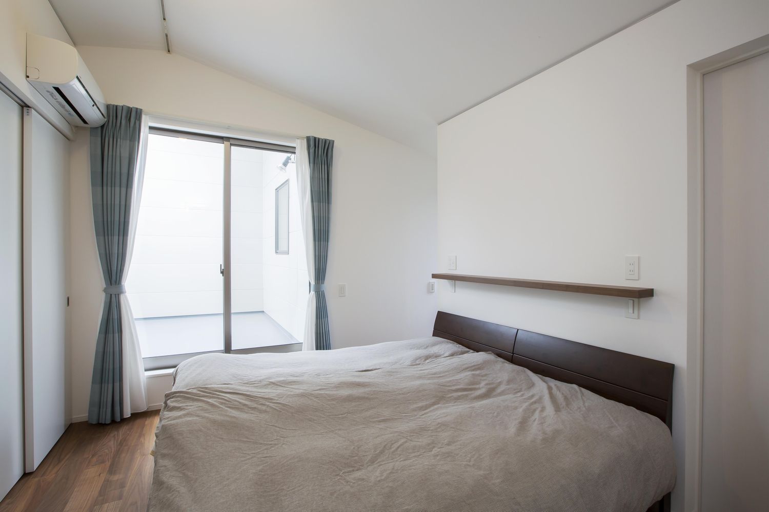 ダブルベッドを一台置くことができるバルコニーに面した寝室・デザイン住宅