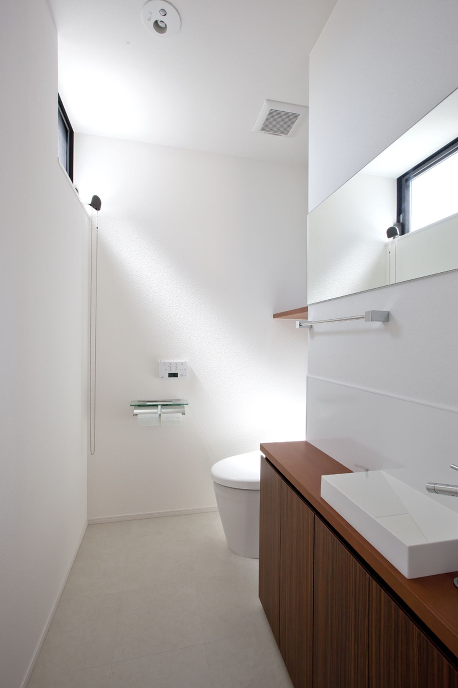 木の手洗いカウンター付きでスリット窓から光が入る広くてシンプルなトイレ・デザイン住宅