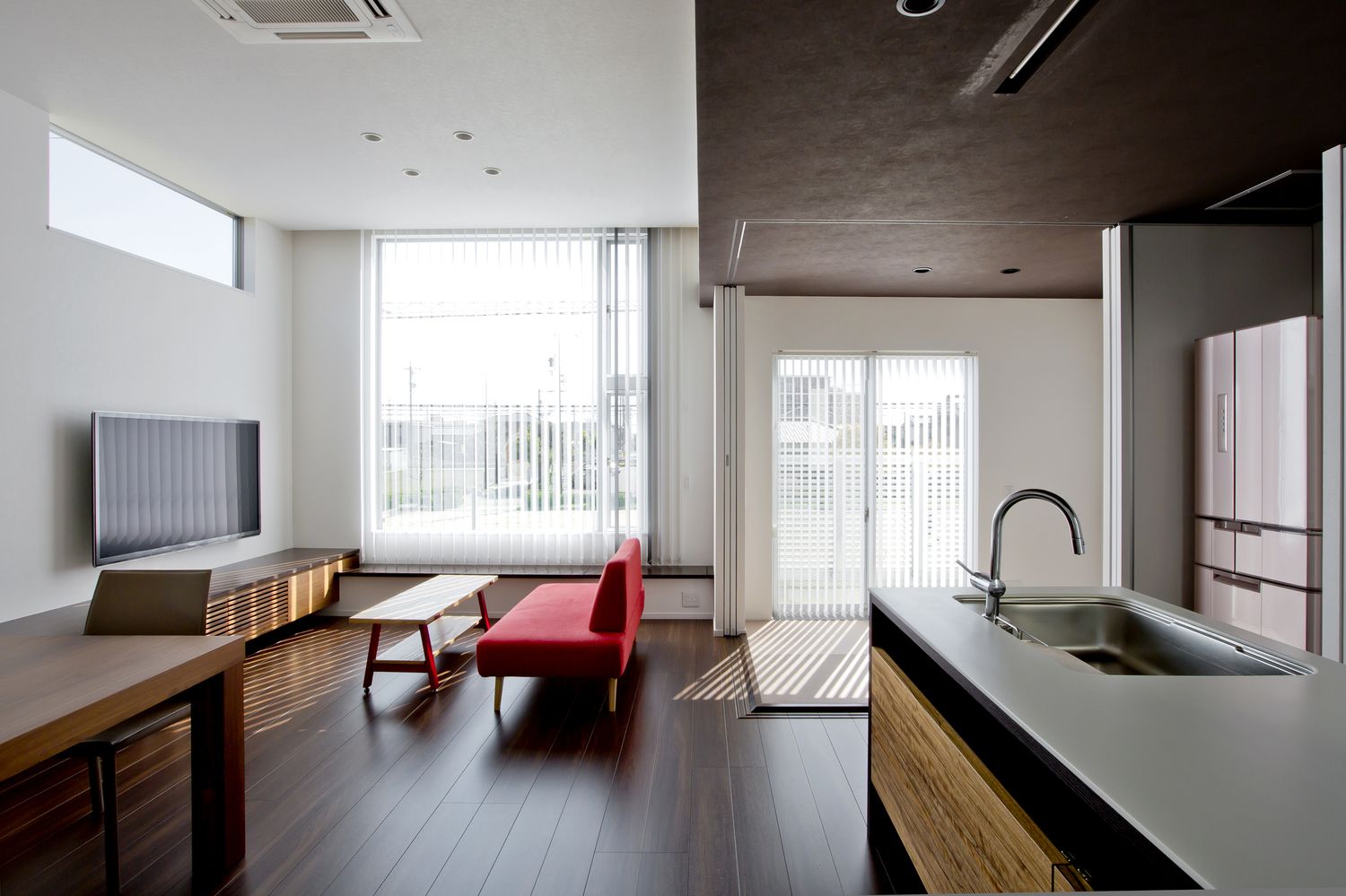 バルコニーに面した大きな窓がある天井の高さと色を切り替えたLDK・デザイン住宅