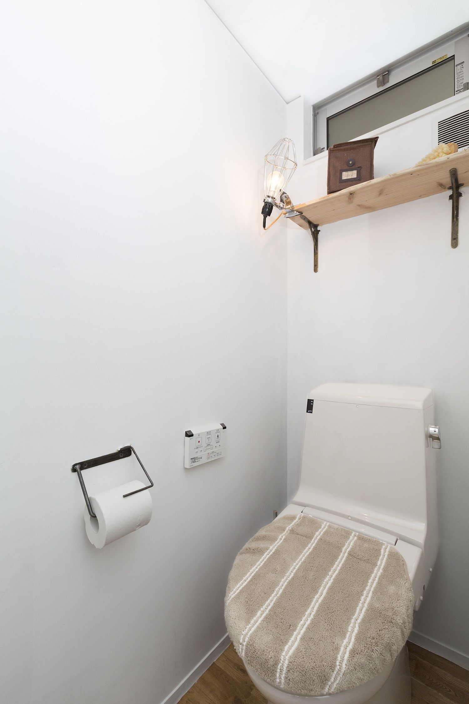 頭上に壁付け棚を取り付けたコンパクトなトイレ・デザイン住宅