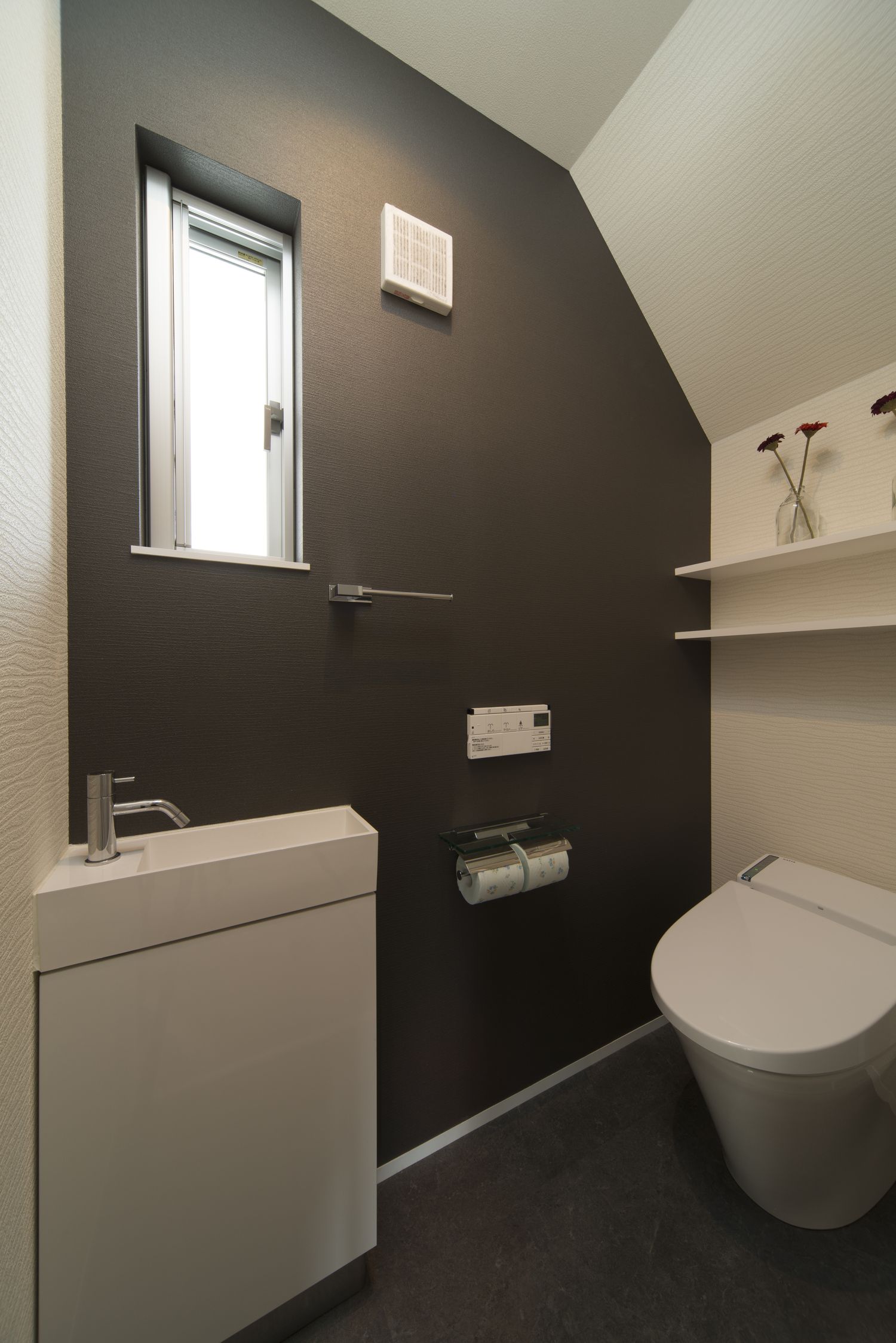 薄型手洗いを取り付けた黒いアクセントクロスがあるトイレ・デザイン住宅