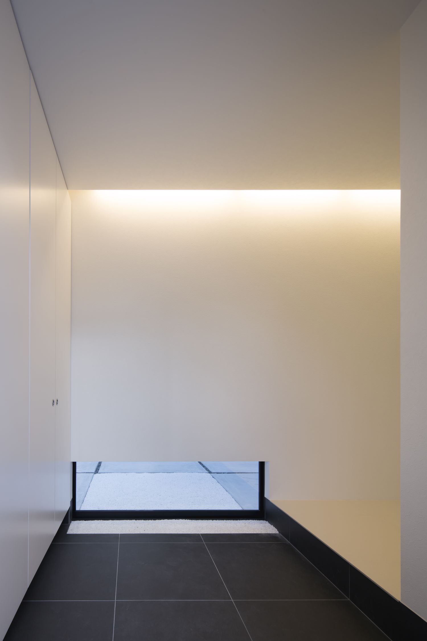 足元に窓を取り付けたモノトーンのシンプルな玄関・デザイン住宅