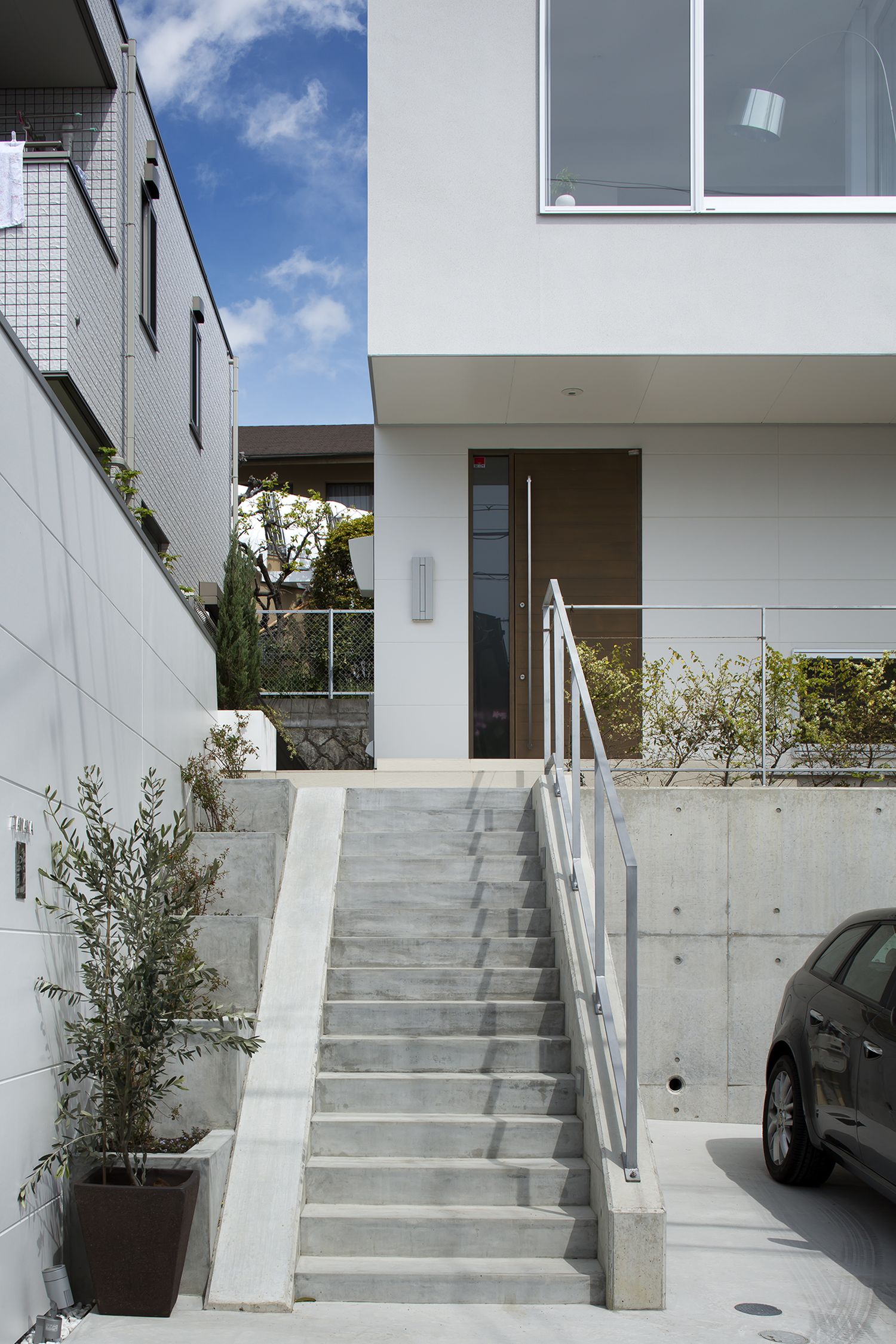 コンクリートの階段のアプローチがある高台の住まい・デザイン住宅