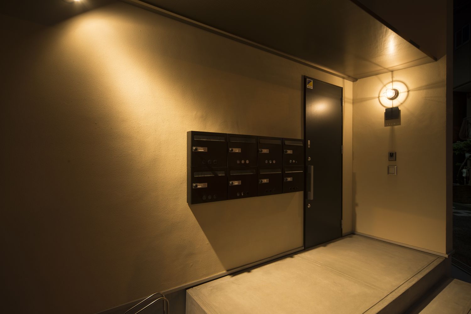 壁に照明が取り付けられたシンプルでおしゃれなアパートの外観・デザイン住宅