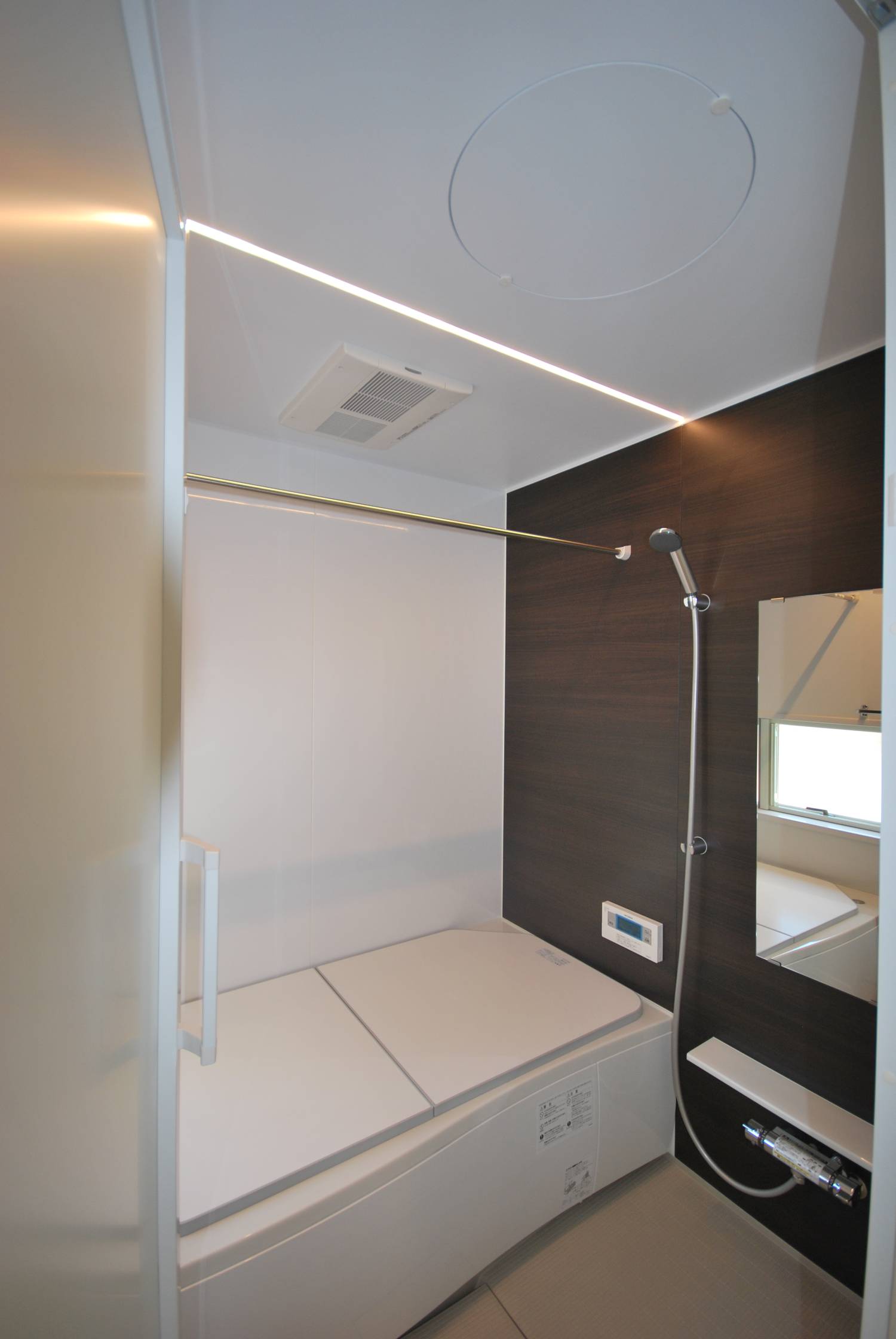 木目の壁が取り付けられたシンプルで落ち着きのある浴室・デザイン住宅