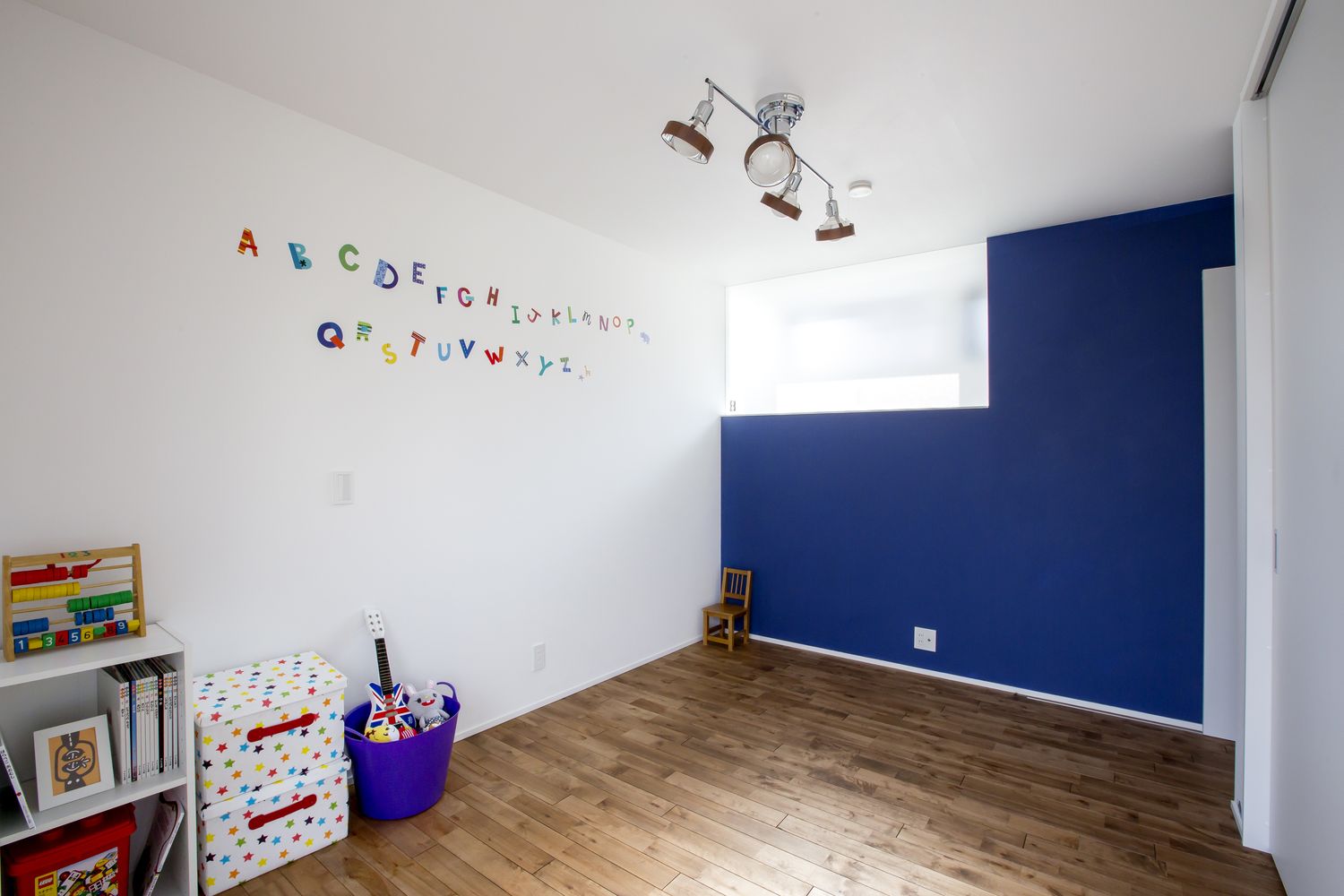 青いアクセントクロスやステッカーが貼られた壁があるかわいい子供部屋・デザイン住宅