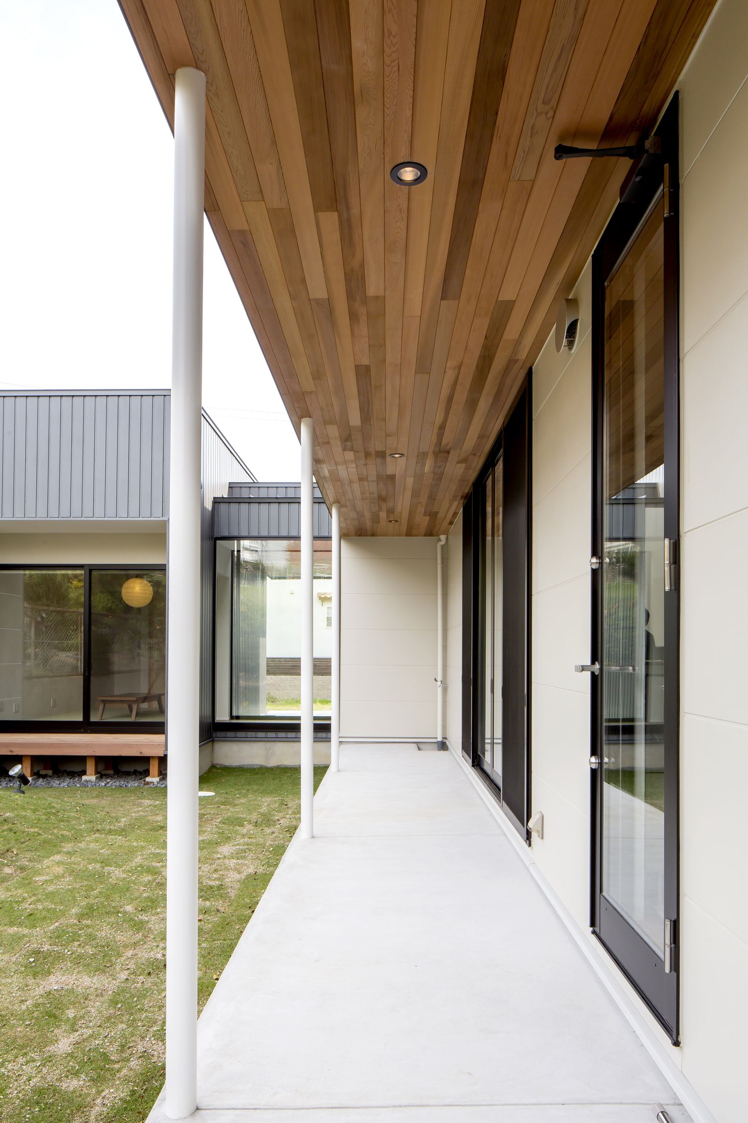 木の軒天井が取り付けられた縁側付きの芝生の庭・デザイン住宅