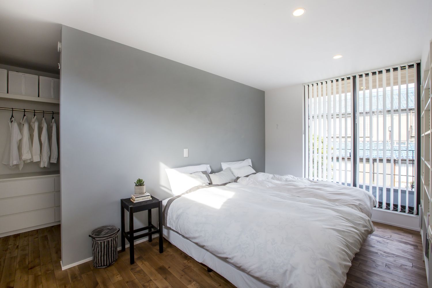 壁で仕切られたウォークインクローゼットがあるダブルベッドを置いた寝室・デザイン住宅