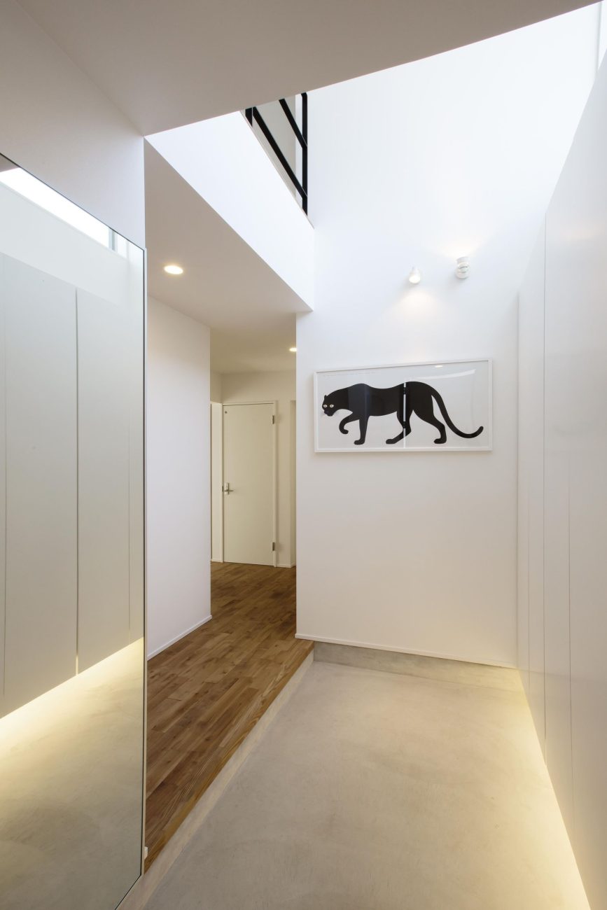 アートが飾られた明るい吹き抜けの玄関・デザイン住宅