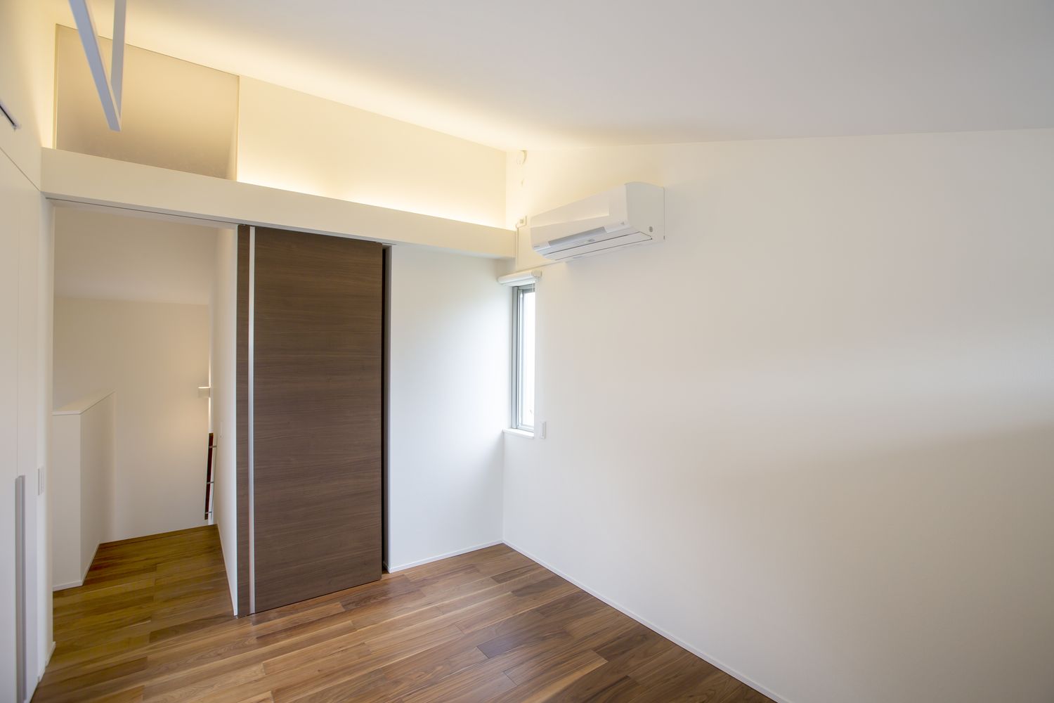 壁際に間接照明を取り付けたホテルライクなシンプルな寝室・デザイン住宅