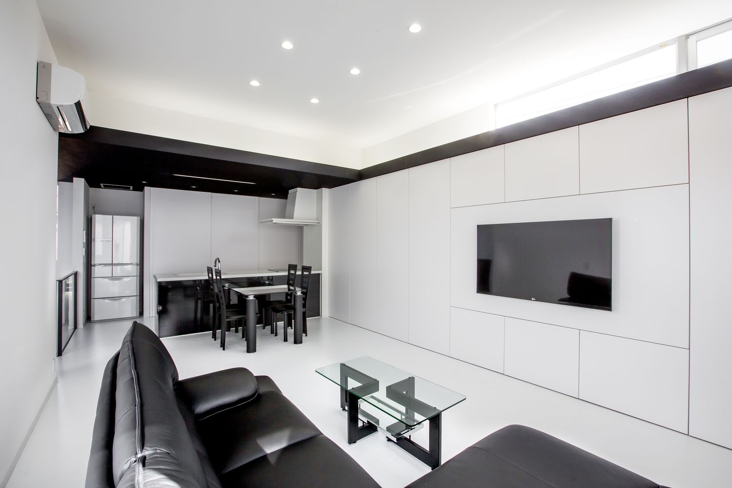 壁かけテレビや黒い革のソファーがあるモノトーンのLDK・デザイン住宅