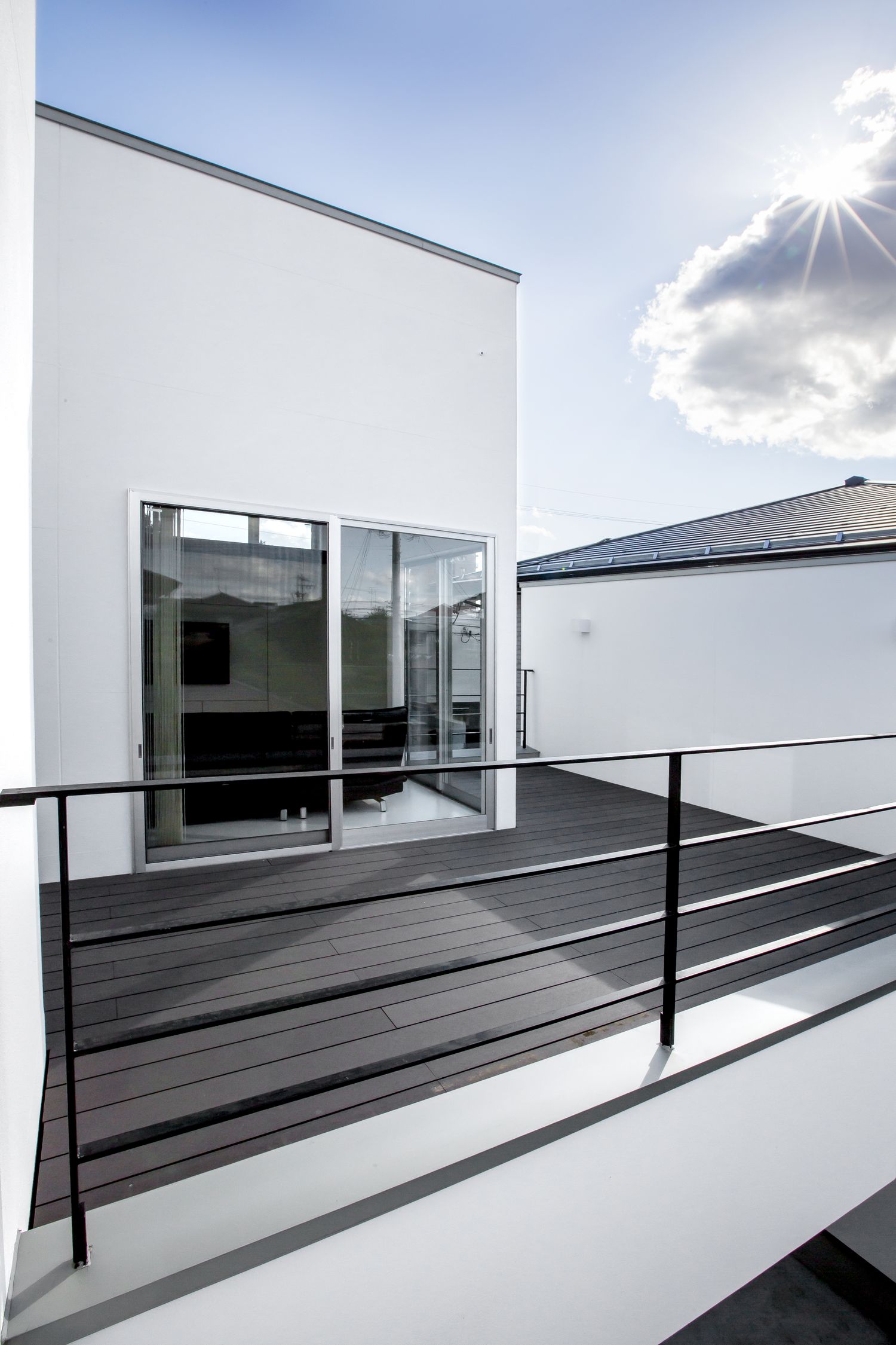 黒いアイアンの手すりを取り付けたシンプルなウッドデッキのバルコニー・デザイン住宅