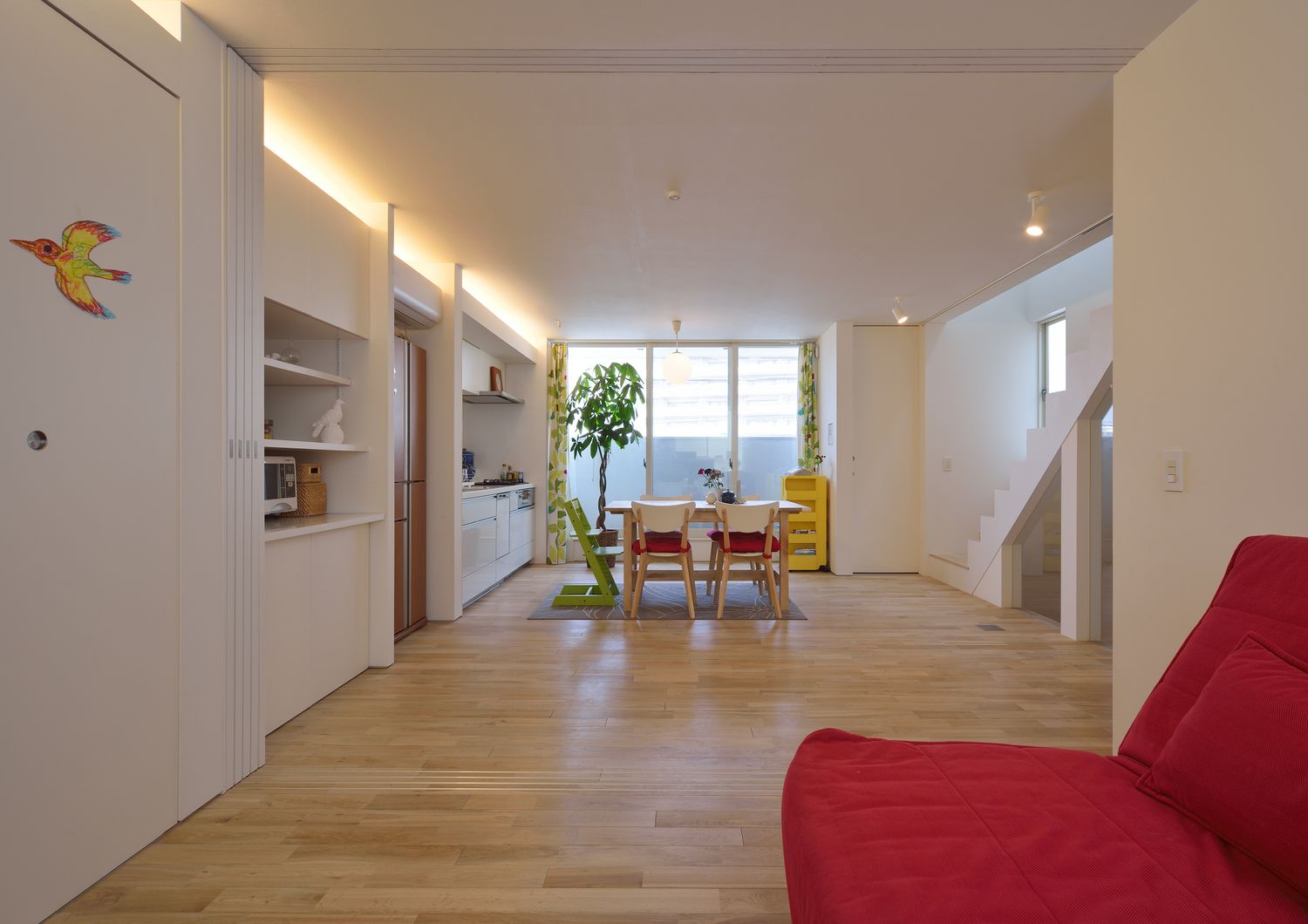 バルコニーに面した大きな窓がある、壁際に間接照明を取り付けたLDK・デザイン住宅