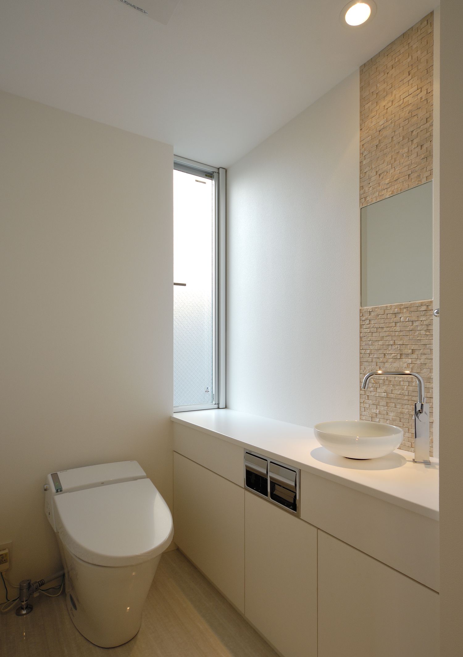 縦長のスリット窓がある手洗いカウンター付きのトイレ・デザイン住宅