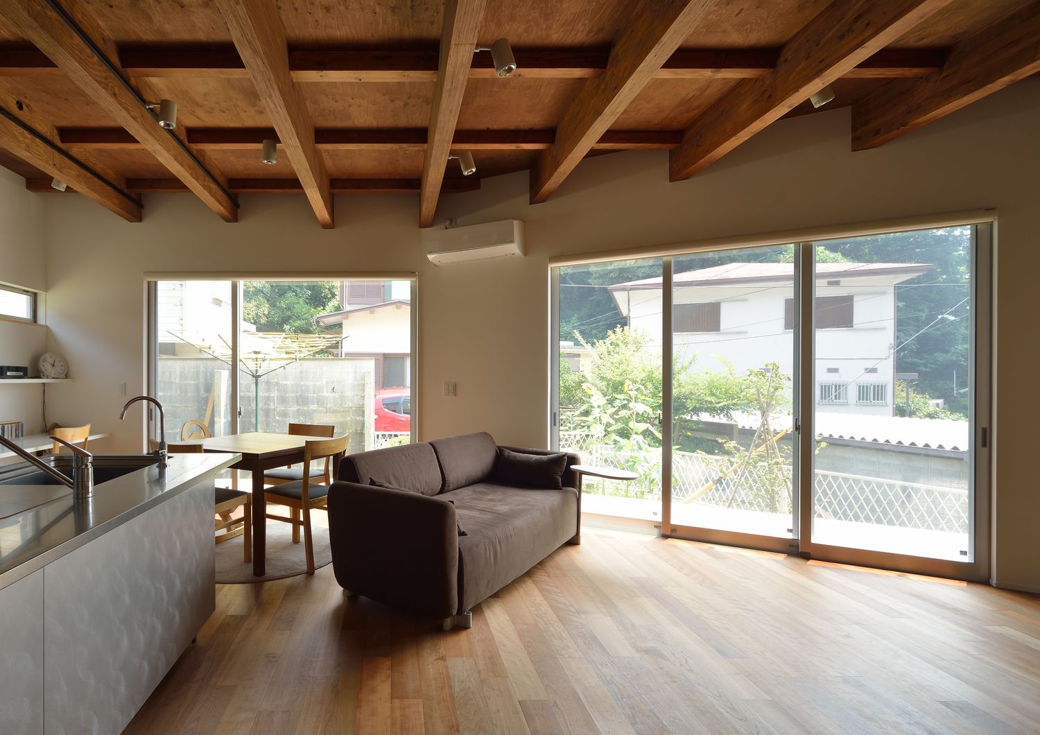 大きな窓から周囲の景色を見ることができる木目の天井のLDK・デザイン住宅