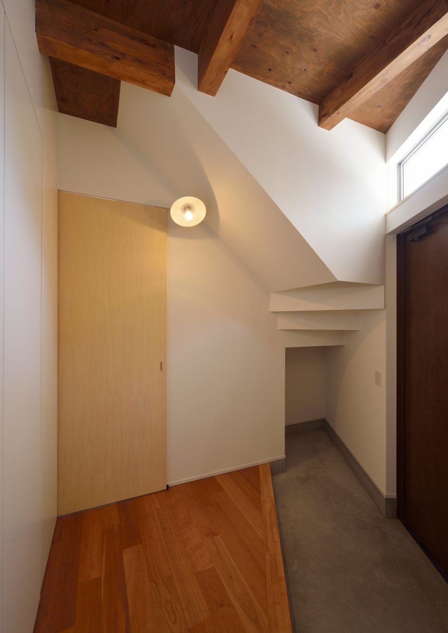 木の天井でシューズインクローゼット付きのシンプルなモルタル玄関・デザイン住宅