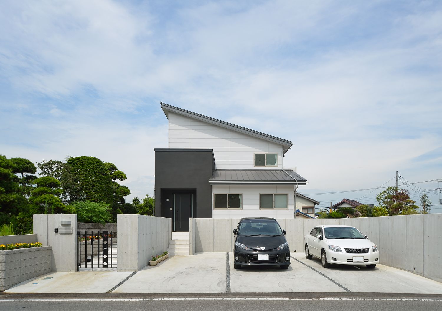 車が二台停められる広い駐車スペースがあるモノトーンの外観の家・デザイン住宅