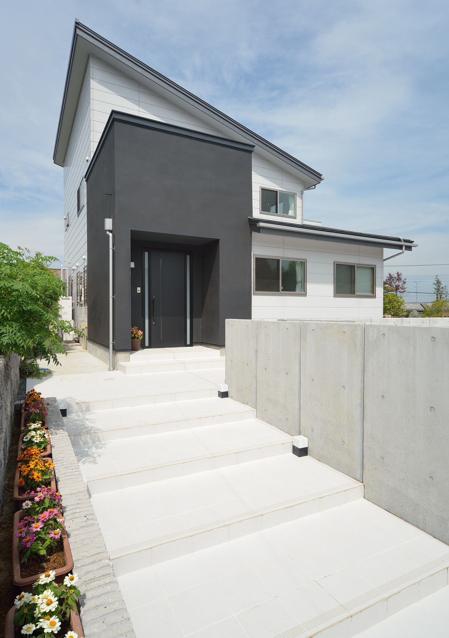 コンクリートの階段アプロ―チの先にあるモノトーンの外観の家・デザイン住宅