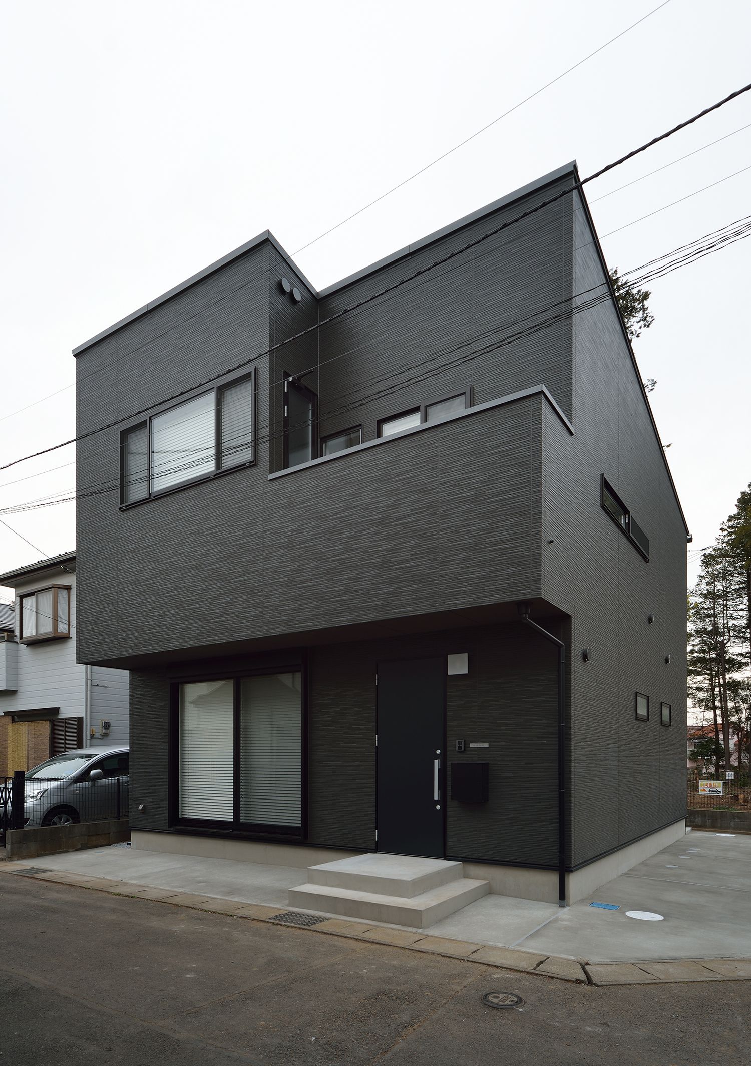 バルコニー付きの黒いキューブ状の外観の家・デザイン住宅