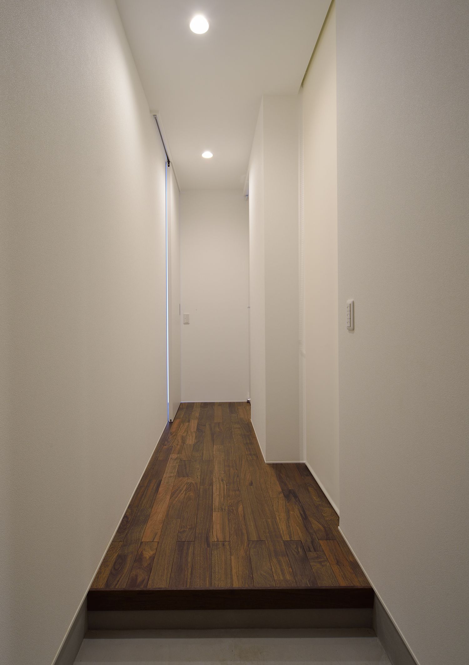 白い壁で木のフローリングのシンプルな廊下・デザイン住宅