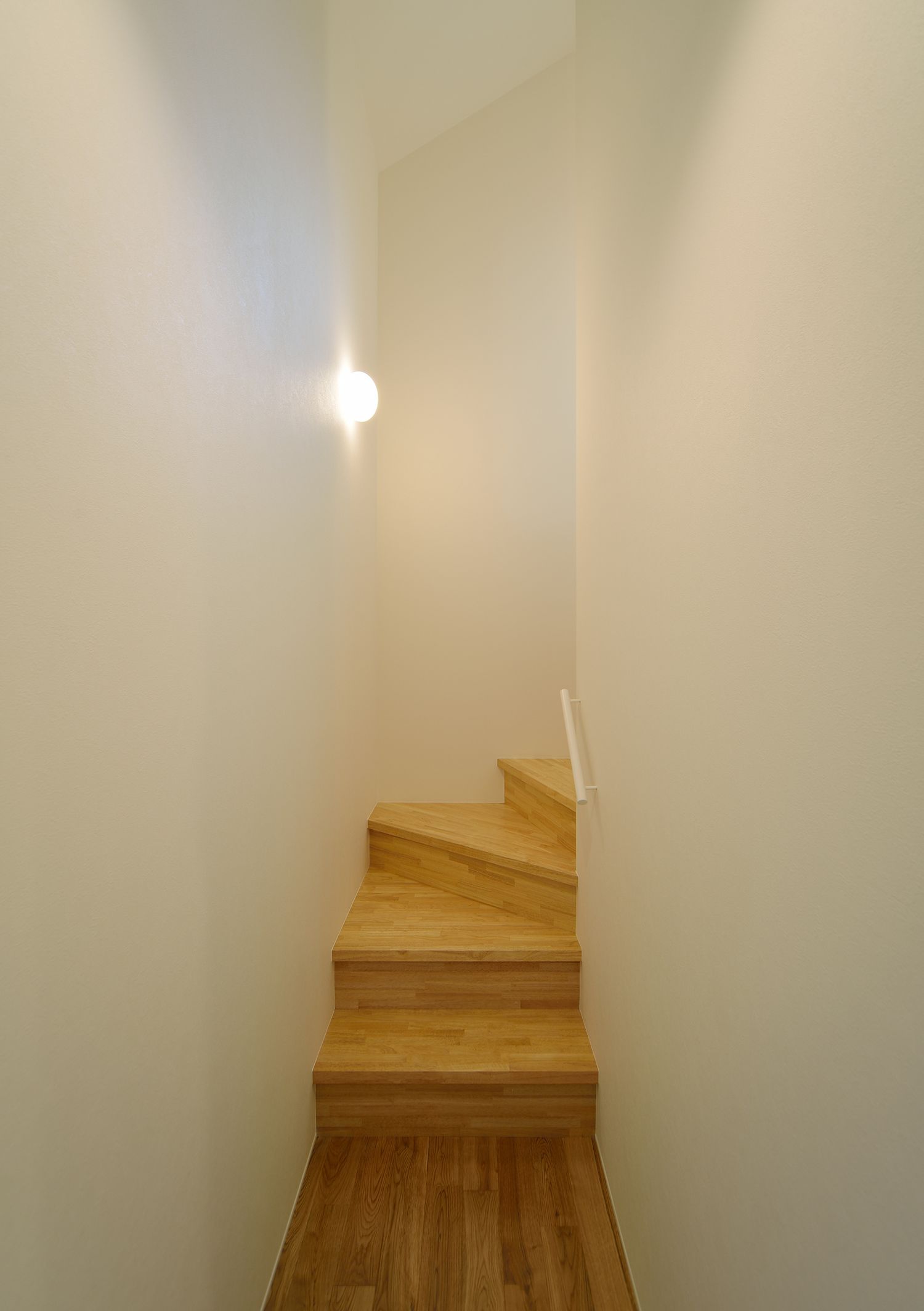 白い壁に囲まれたシンプルな木製の箱型階段・デザイン住宅