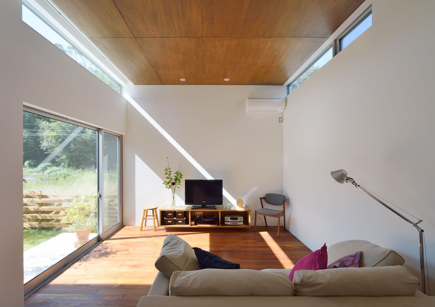 中庭に面した大きな窓や天井近くの窓がある明るく開放的な高天井のLDK・デザイン住宅