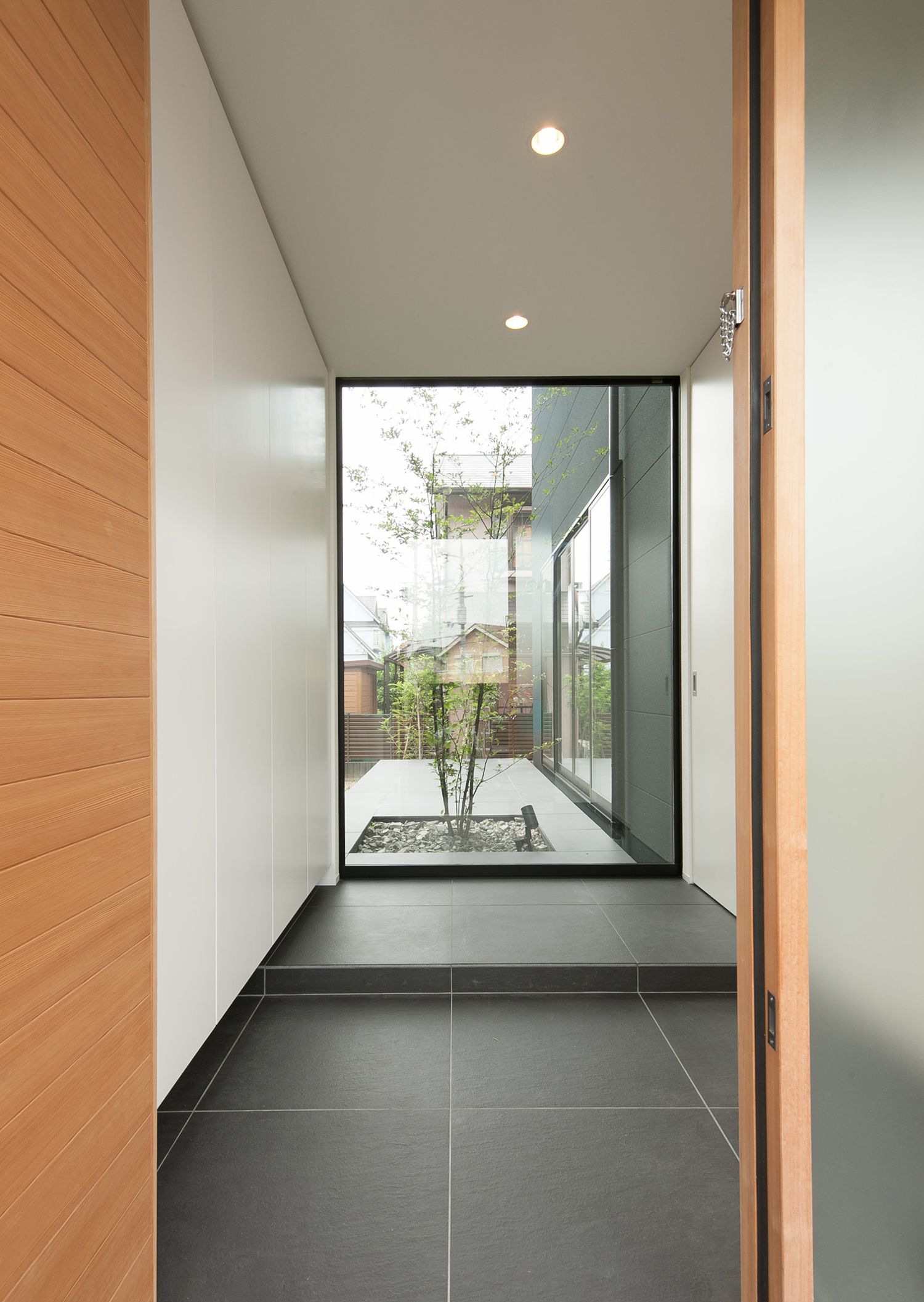 正面の大きな窓からテラスが見える開放感のあるタイル玄関・デザイン住宅