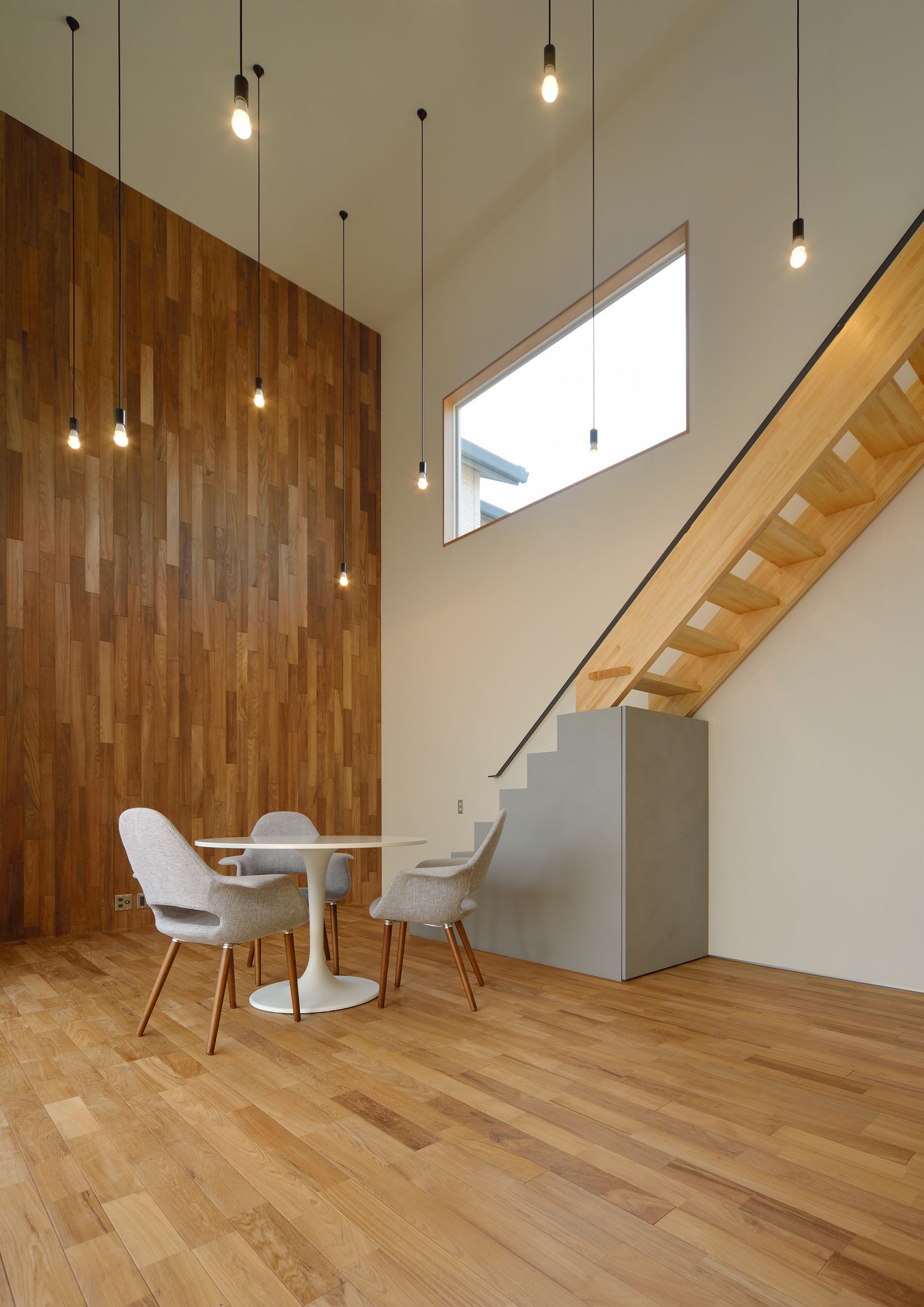 吹き抜けで天井から細いペンダントライトが沢山吊るされているLDK・デザイン住宅