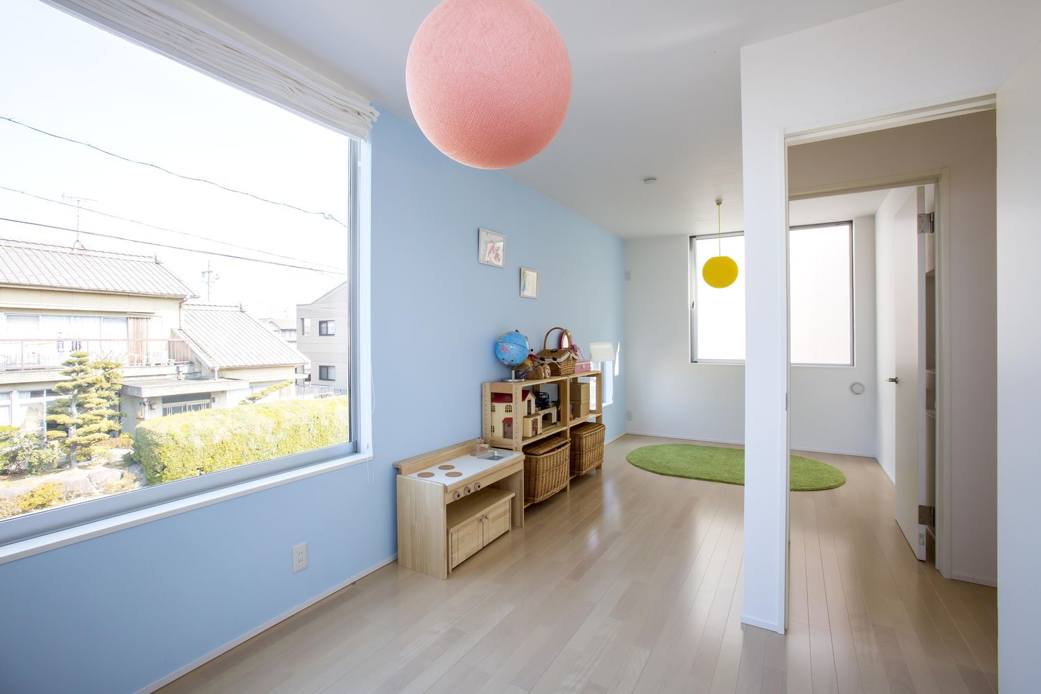 青い壁に大きな窓が取り付けられたかわいい子供部屋・デザイン住宅