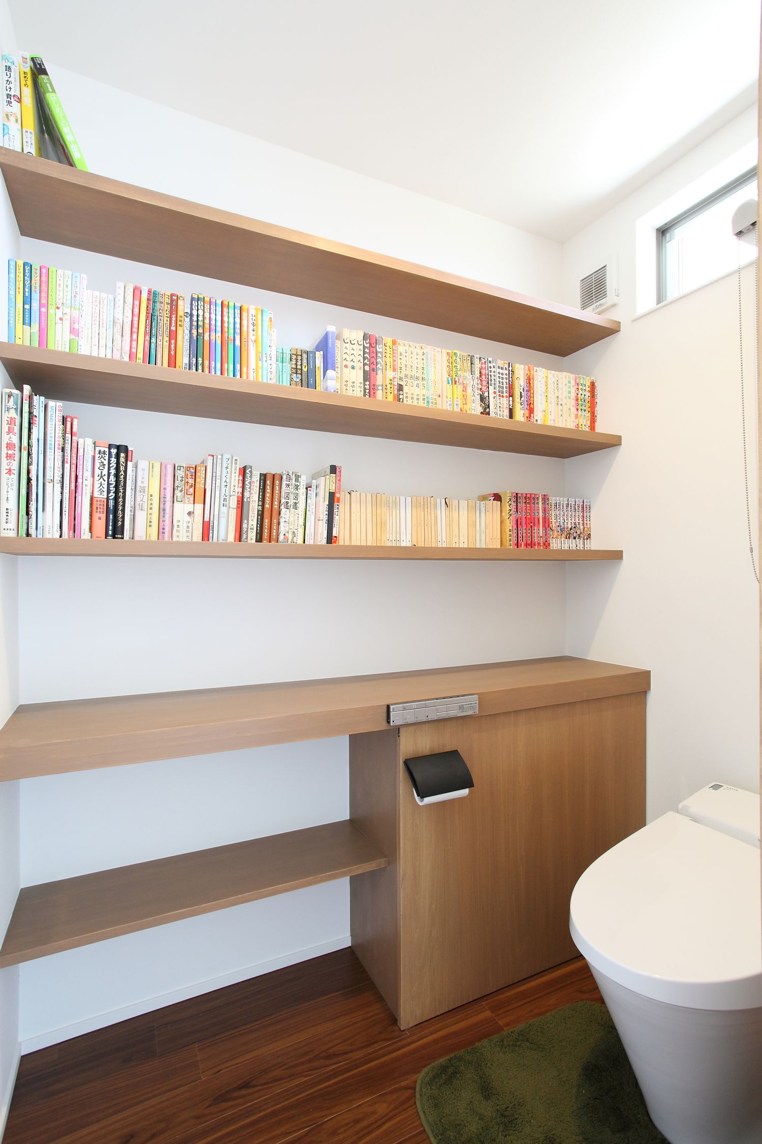 壁付けの本棚を取り付けたトイレ・デザイン住宅