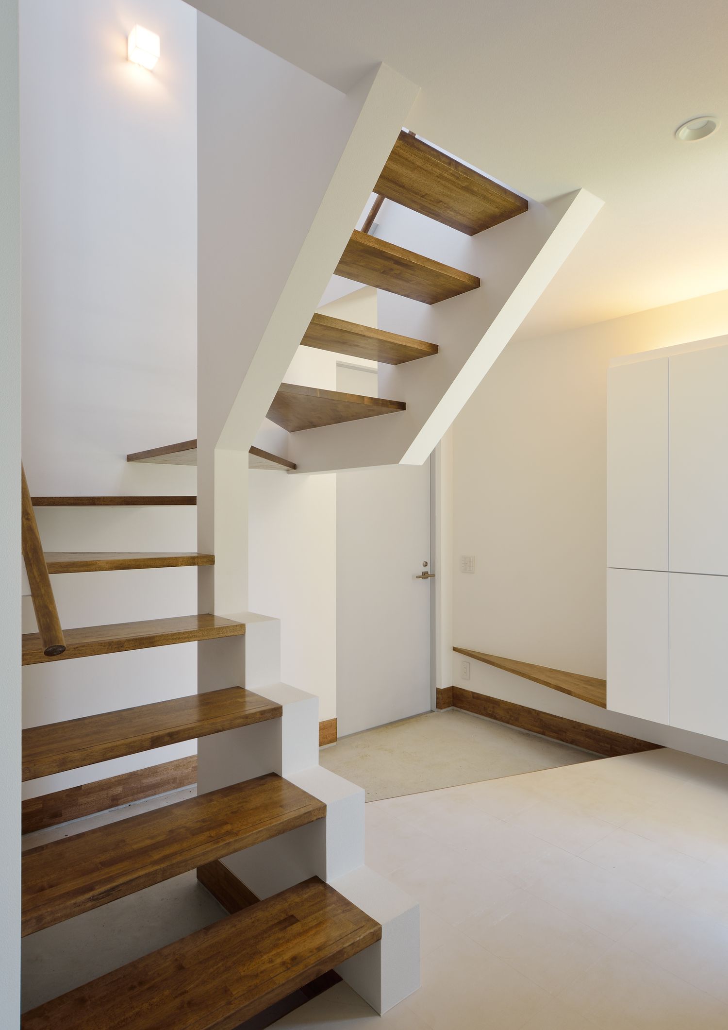 玄関を横切る木のスケルトン階段・デザイン住宅