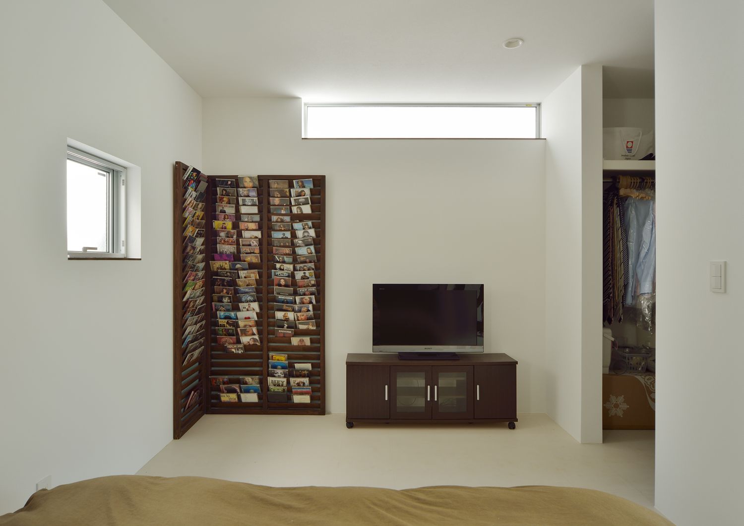 天井近くにスリット窓が取り付けられた本棚付きの寝室・デザイン住宅