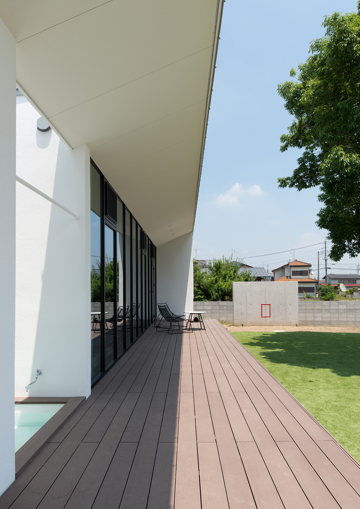 芝生の庭に面する、テーブルと椅子が置かれたウッドデッキのテラス 注文住宅・デザイン住宅建築実例_『CASE634 アトリエを持つ家』_テラス・バルコニー