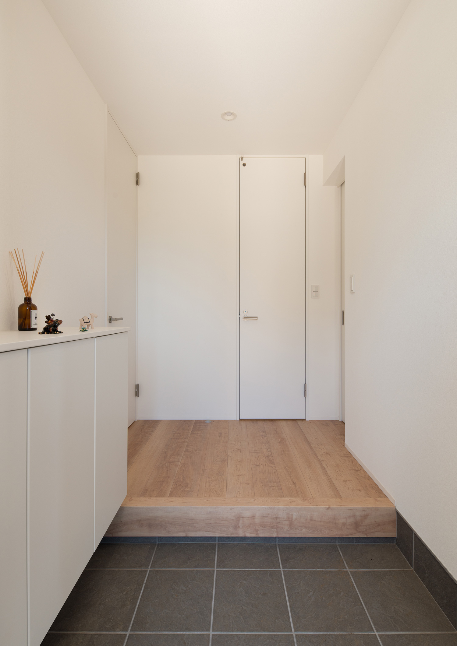 シューズボックス付きの黒いタイルの玄関の先にフローリングのフロアが広がっている様子・デザイン住宅 注文住宅・デザイン住宅建築実例_『CASE638 「BLACK BOX」』_玄関