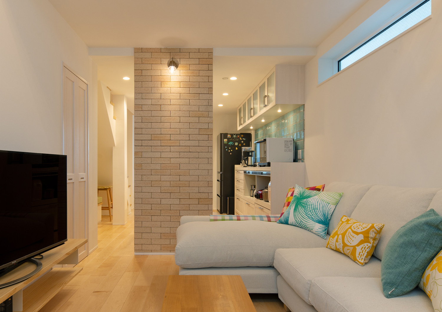 間接照明が取り付けられたタイルの壁がある、L字ソファーが置かれたLDK・デザイン住宅 注文住宅・デザイン住宅建築実例_『CASE641 だんだん』_LDK