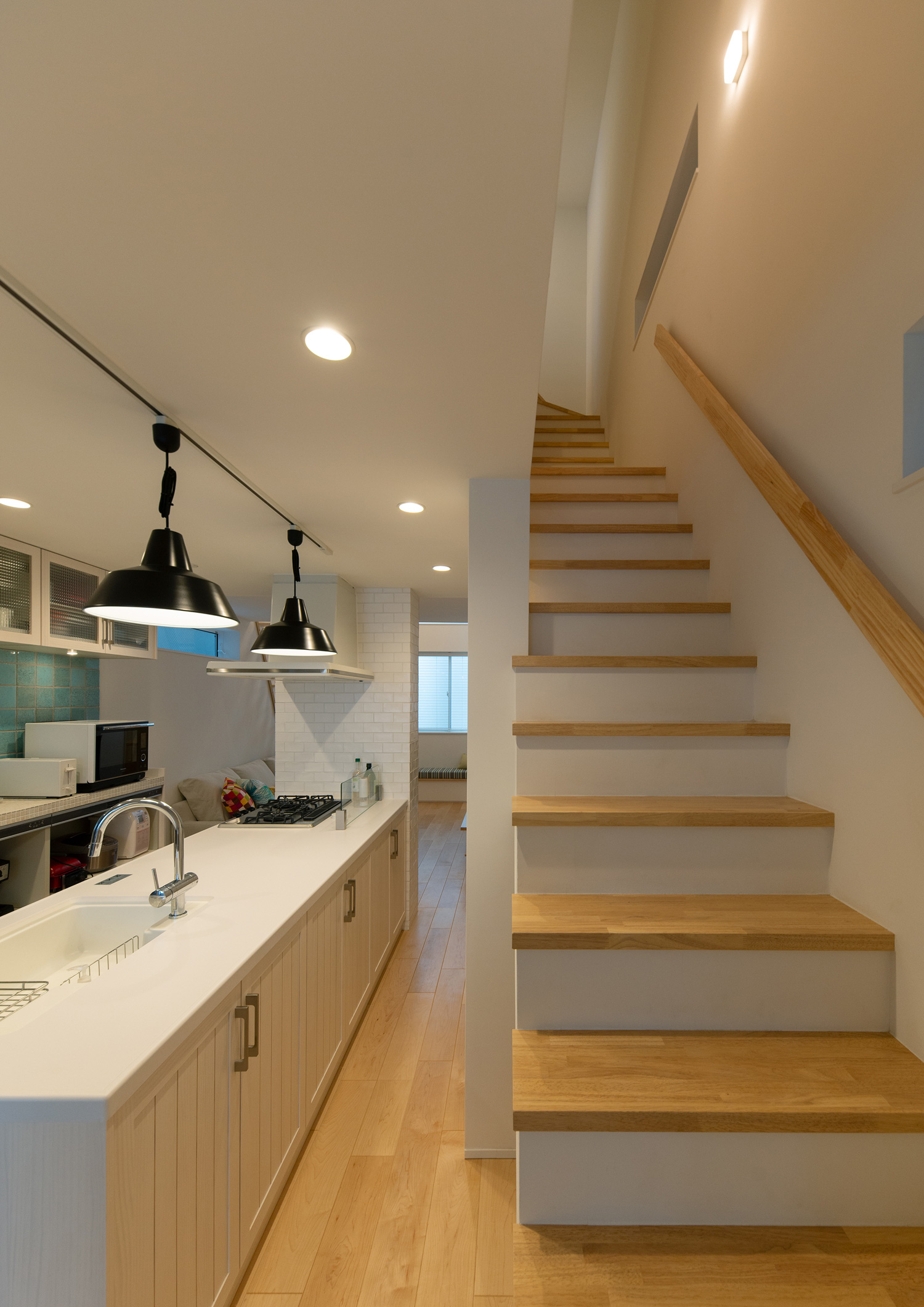 白いペニンシュラキッチンの前に設けられた木の箱型階段・デザイン住宅 注文住宅・デザイン住宅建築実例_『CASE641 だんだん』_階段