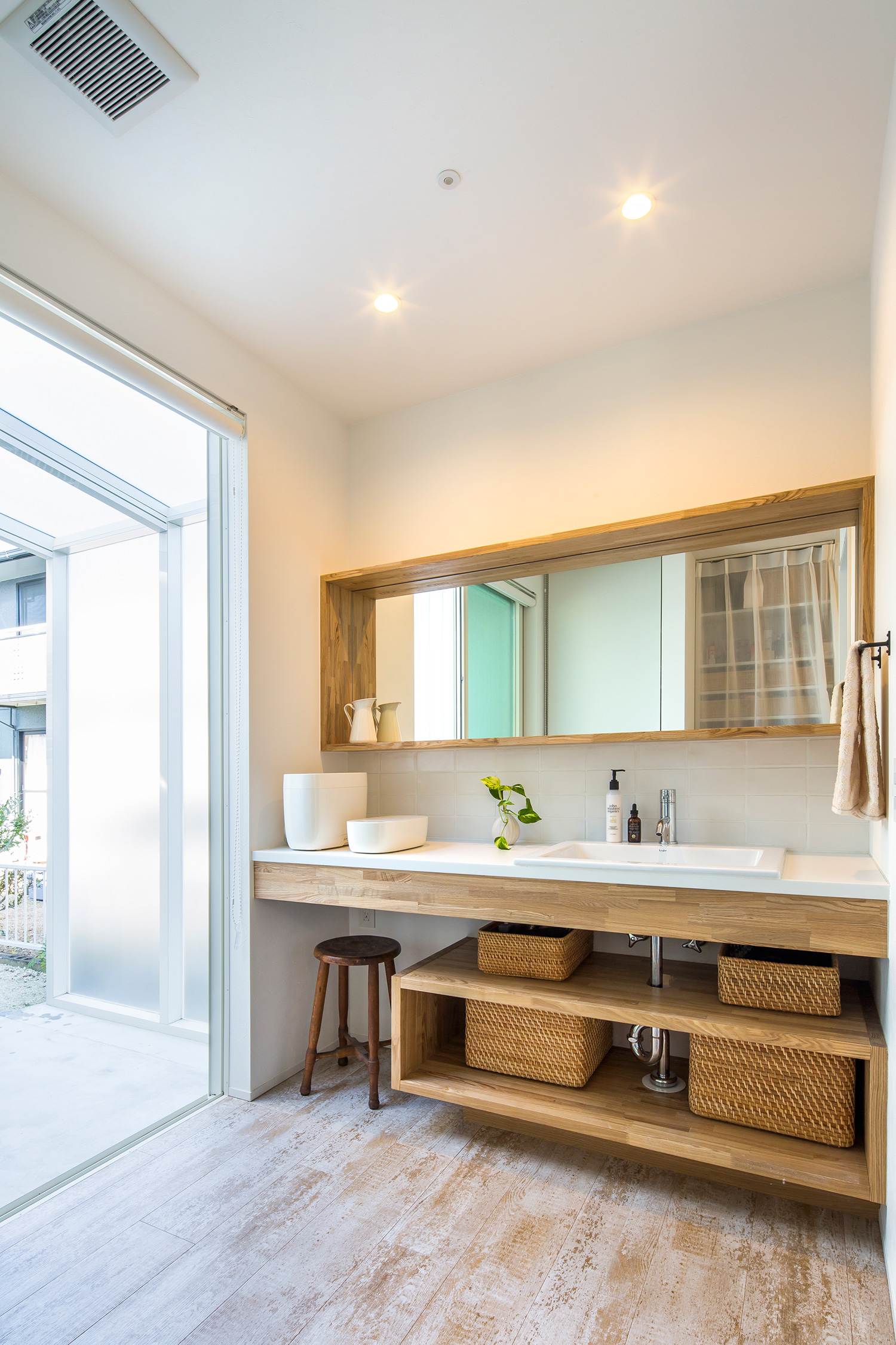 洗面台の下に木の収納棚を設けた、ベランダに隣接する洗面所・デザイン住宅 注文住宅・デザイン住宅建築実例_『CASE635 三角屋根でつながる家』_浴室・洗面所