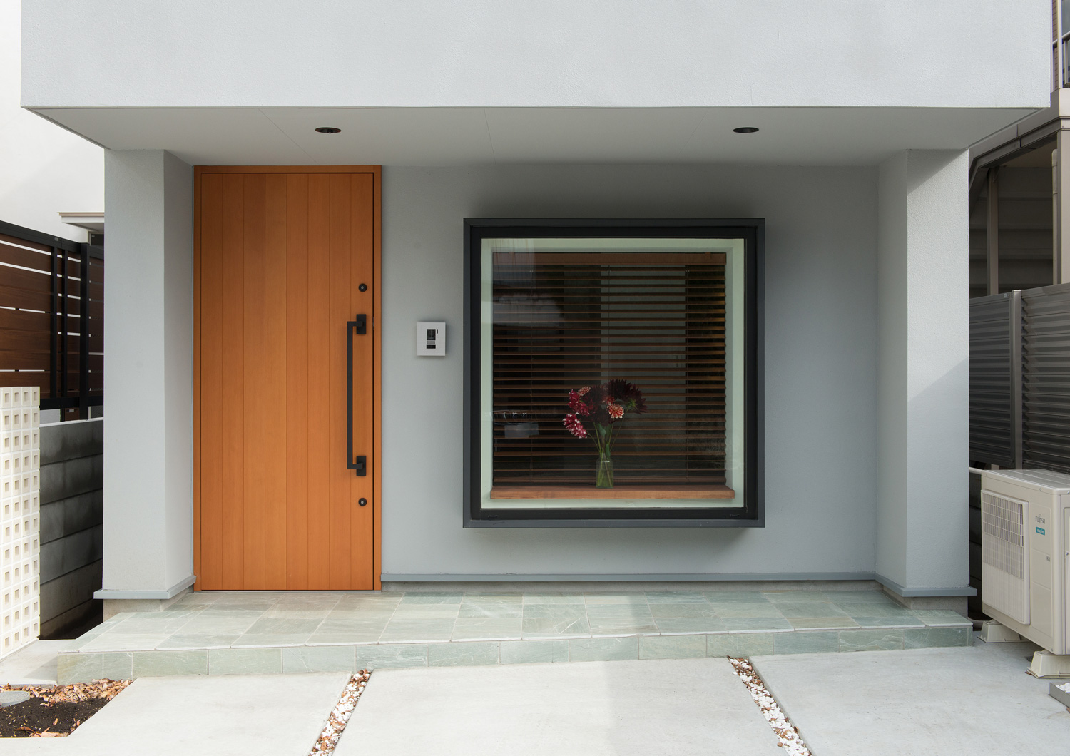 木目の玄関扉の横に、花が飾られた出窓がある住宅・デザイン住宅 注文住宅・デザイン住宅建築実例_『CASE643 だて窓のハウス』_外観