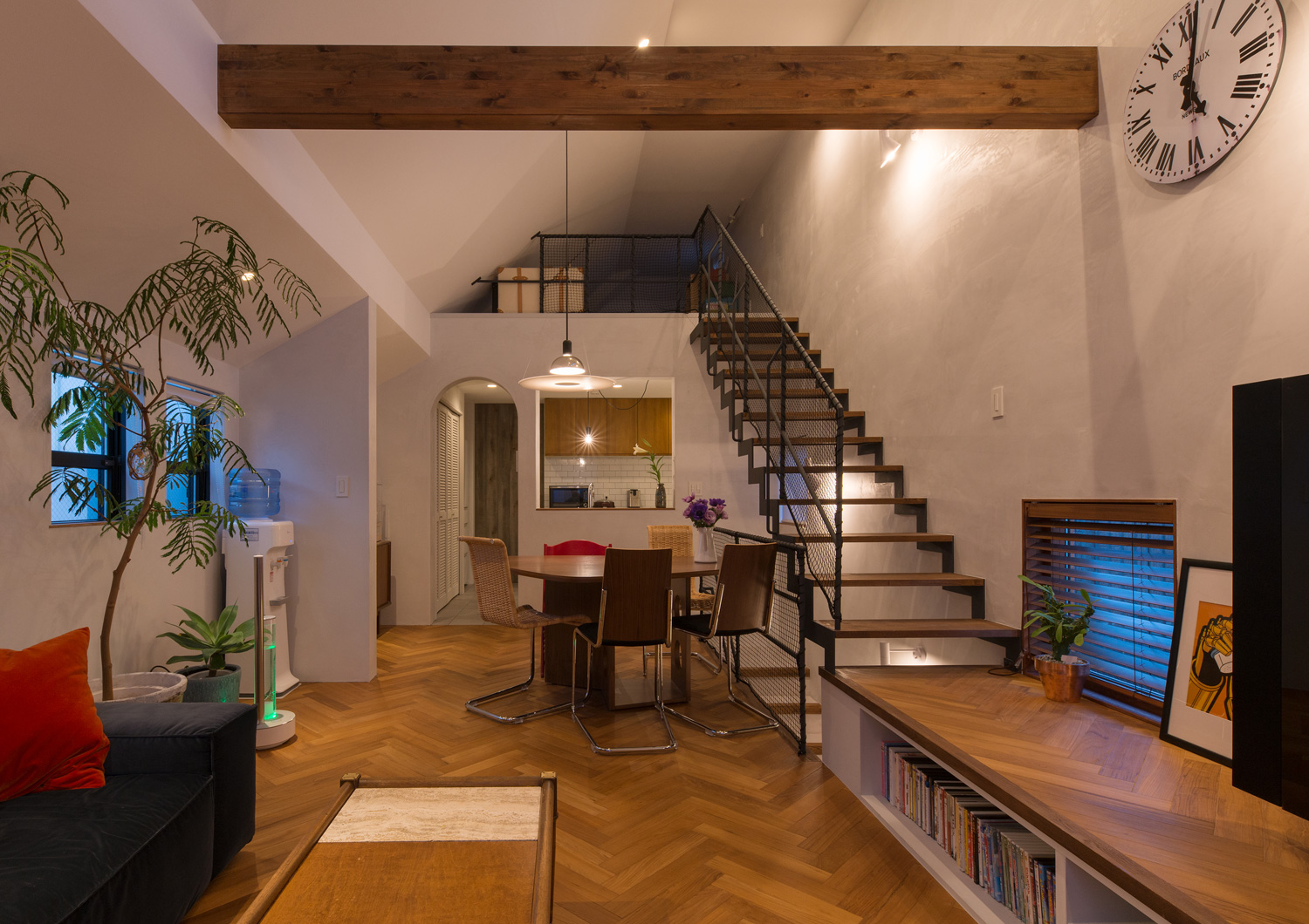 アーチ壁や正方形にくりぬかれた壁の向こうにキッチンがあるLDK壁に取り付けられたスポットライトやペンダントに照らされるヘリンボーン柄の床のLDK・デザイン住宅 注文住宅・デザイン住宅建築実例_『CASE643 だて窓のハウス』_LDK