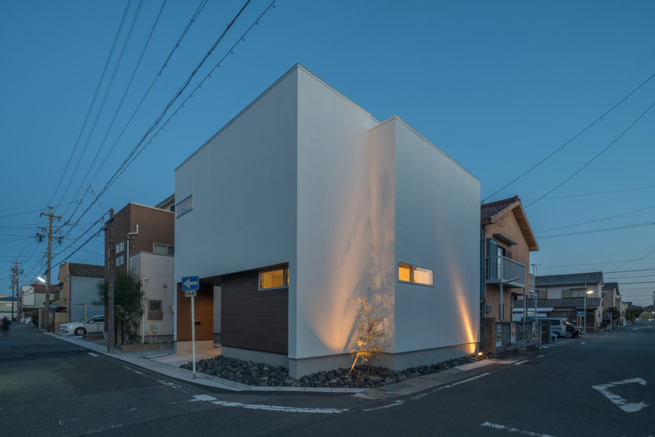 角地に建つ住宅の白い外壁に植栽がライトアップされている様子・デザイン住宅 注文住宅・デザイン住宅建築実例_『CASE645 フレームハウス』_外観