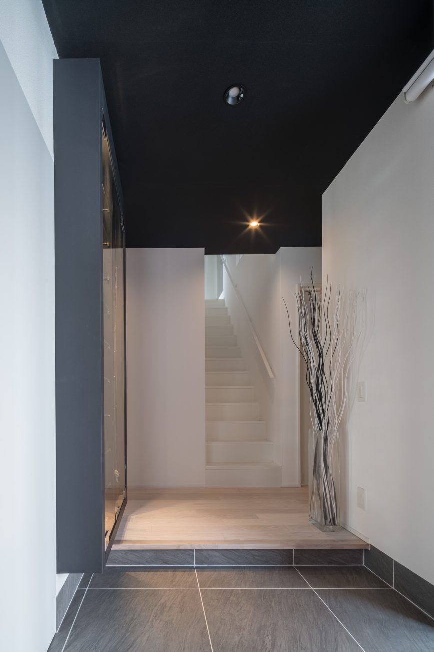 正面に白い壁と白い階段が見える、タイル張りの玄関・デザイン住宅 注文住宅・デザイン住宅建築実例_『CASE645 フレームハウス』_玄関