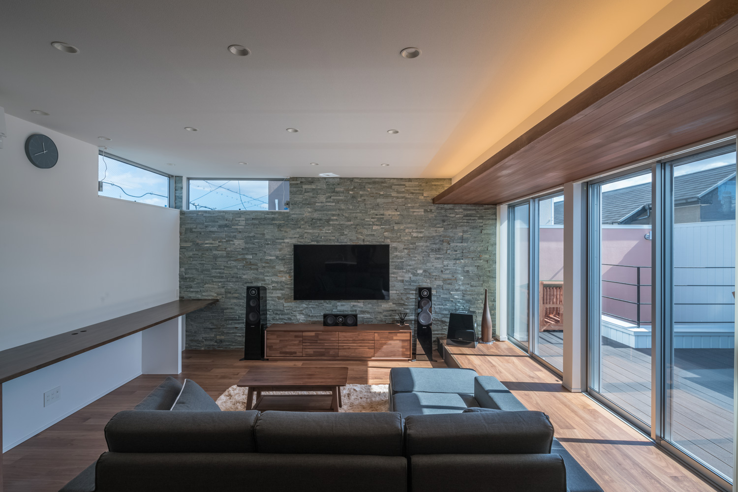 石のアクセントウォールにテレビが掛けられた、壁付けデスクのあるLDK・デザイン住宅 注文住宅・デザイン住宅建築実例_『CASE645 フレームハウス』_LDK